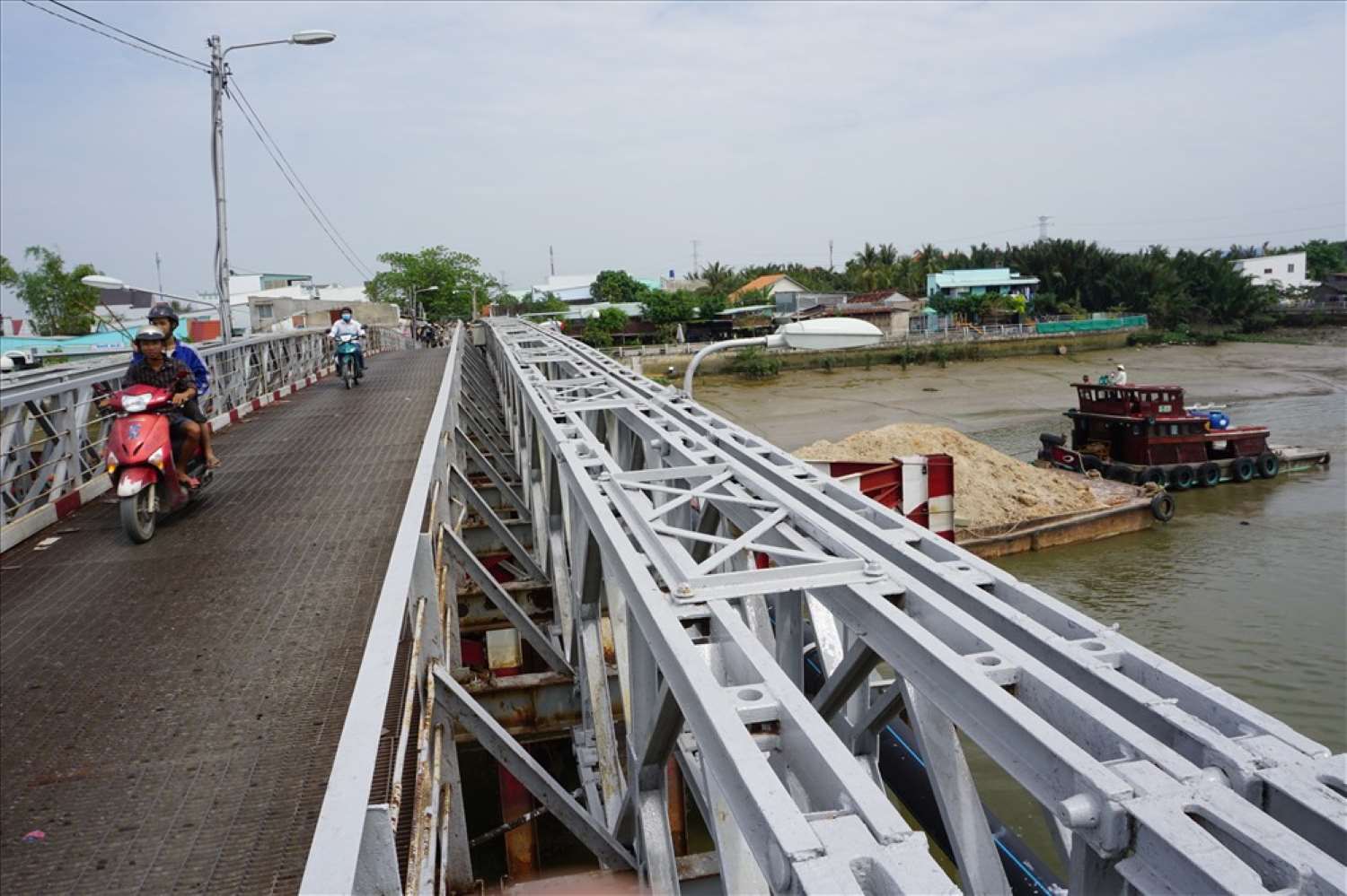 Một chiếc phà cỡ lớn chở đầy cát luồn lách chui qua cầu Rạch Dơi. Ảnh: Minh Quân